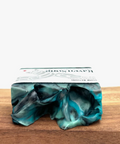 Marbled green and blue soap bar on a wooden surface with a white background