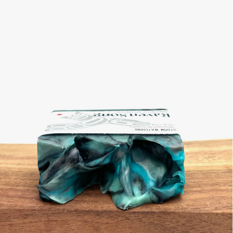 Marbled green and blue soap bar on a wooden surface with a white background