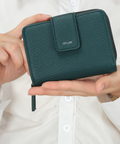 Green wallet held in a hand with a white background