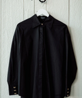 Black shirt on a hanger against a light wooden panel background