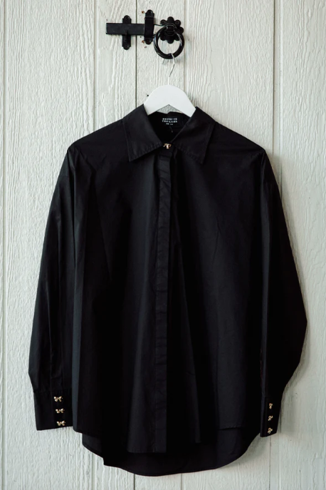 Black shirt on a hanger against a light wooden panel background