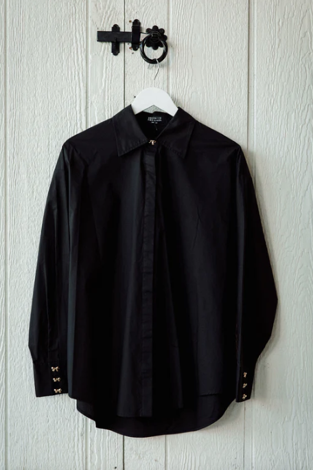 Black shirt on a hanger against a light wooden panel background
