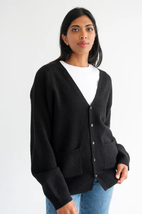 Woman wearing a black cardigan over a white shirt on a white background