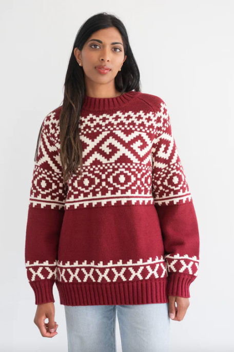 Woman wearing a red and white patterned sweater on a plain background