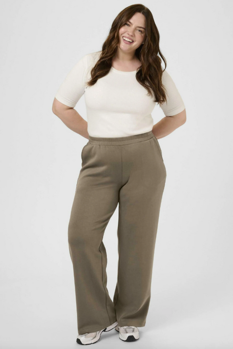 Woman wearing a white top and brown pants on a white background