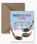 Hockey-themed birthday card with sticks, puck, and goal on a blue background, accompanied by a brown envelope.