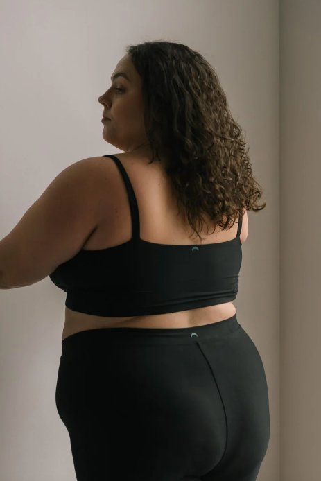 Person wearing a black sports bra and leggings against a neutral background