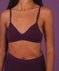 Person wearing a purple sports bra and shorts against a purple background