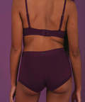 Person wearing a dark purple bikini set against a matching purple background