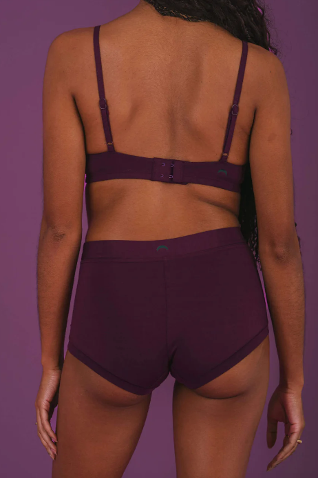 Person wearing a dark purple bikini set against a matching purple background