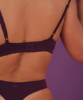 Person wearing a dark purple bikini against a purple background