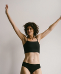 Person wearing a black sports bra and underwear set against a plain background