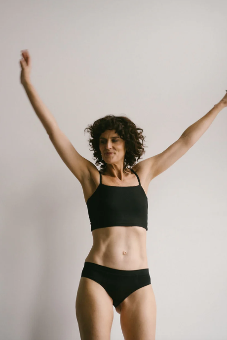 Person wearing a black sports bra and underwear set against a plain background