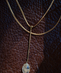 Gold necklace with a pendant on a textured brown background