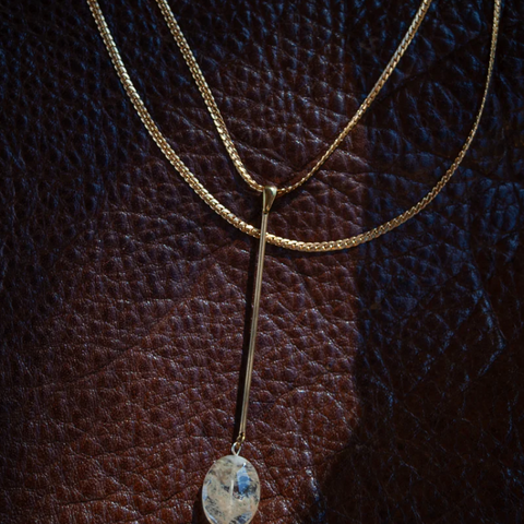 Gold necklace with a pendant on a textured brown background