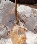 Gold pendant with a stone on a lace fabric background