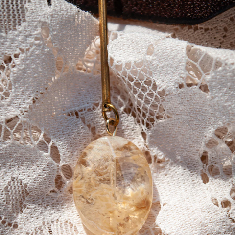 Gold pendant with a stone on a lace fabric background