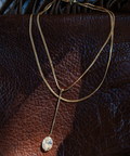 Gold necklace with a pendant on a brown leather surface