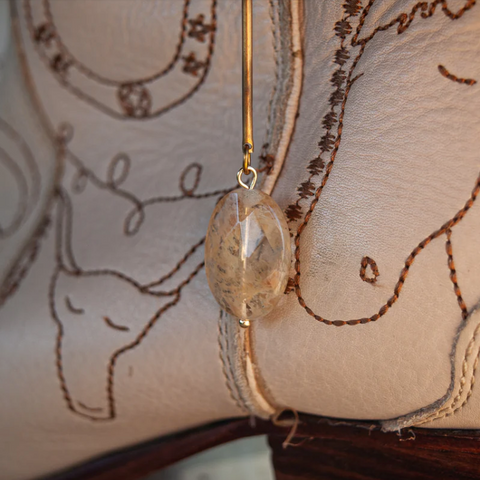 Close-up of a decorative earring on a embroidered fabric background