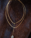 Gold necklace with a pendant on a brown leather surface