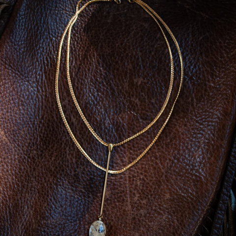 Gold necklace with a pendant on a brown leather surface