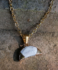 Gold necklace with a triangular pendant on a textured stone background