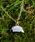 Necklace with a white pendant on a grass background