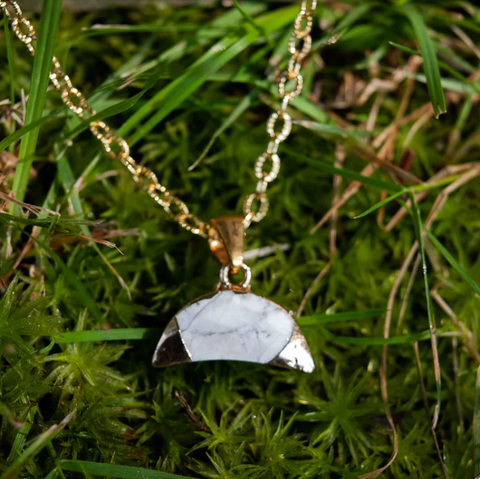 Necklace with a white pendant on a grass background