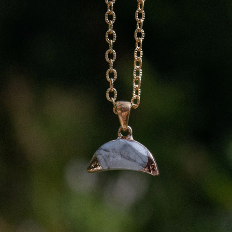 Necklace with a half-circle pendant on a blurred green background