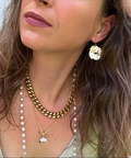 Close-up of a woman wearing gold jewelry including earrings, necklaces, and bracelets.