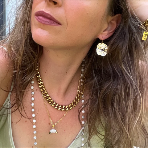 Close-up of a woman wearing gold jewelry including earrings, necklaces, and bracelets.
