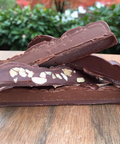 Chocolate bar with nuts on a wooden surface outdoors