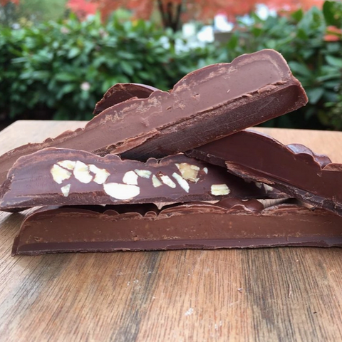 Chocolate bar with nuts on a wooden surface outdoors