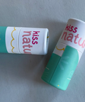Two 'kiss nature' lip balms on a light gray background