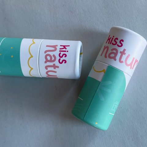 Two 'kiss nature' lip balms on a light gray background