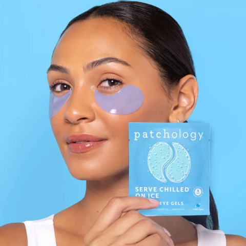 Woman holding a package of patchology eye gels with a blue background