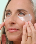 Woman applying eye patches with a teal background
