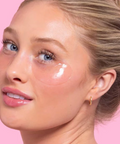 Woman with cosmetic products on her face against a pink background