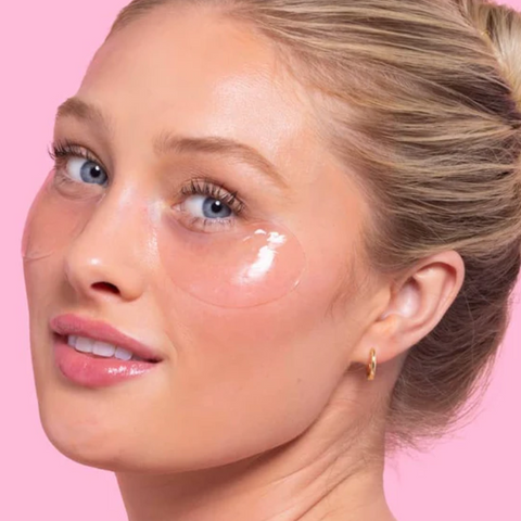 Woman with cosmetic products on her face against a pink background