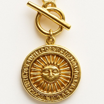 Gold pendant with sun design and chain on a white background