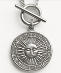 Silver pendant with sun design on a white background