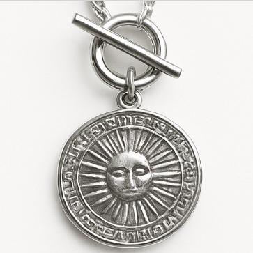 Silver pendant with sun design on a white background