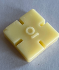 Yellow plastic component with cutouts on a gray background