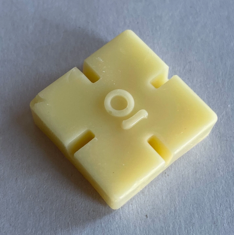Yellow plastic component with cutouts on a gray background
