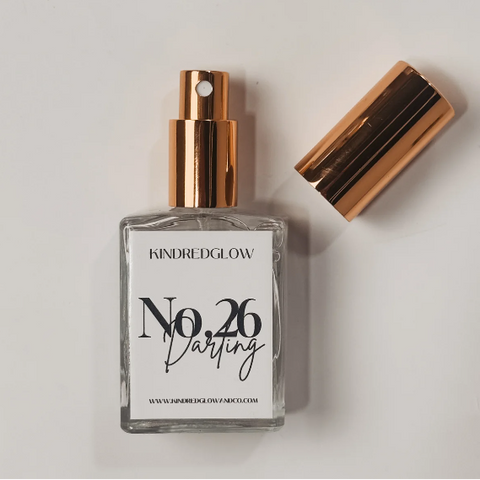 Perfume bottle with gold cap and 'Kindred Glow' label on a light background