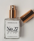Perfume bottle with rose gold cap and clear glass body on a light gray background