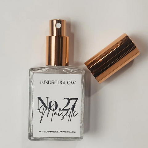 Perfume bottle with rose gold cap and clear glass body on a light gray background
