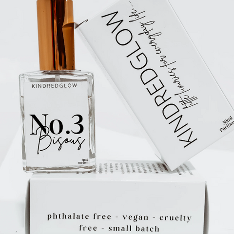 Perfume bottle labeled 'No. 3 Bisous' by Kindred Glow with packaging in the background.