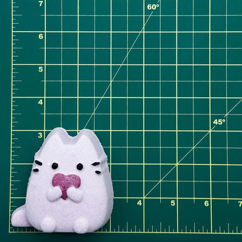 White plush toy with black accents on a green cutting mat with grid lines