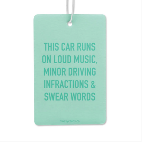 A green car air freshener with text stating 'This car runs on loud music, minor driving infractions & swear words'.